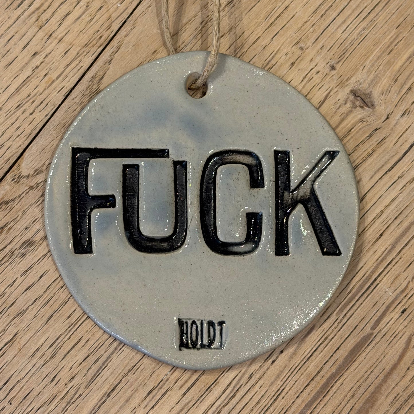Ophæng med tekst; ‘FUCK’, lys blå