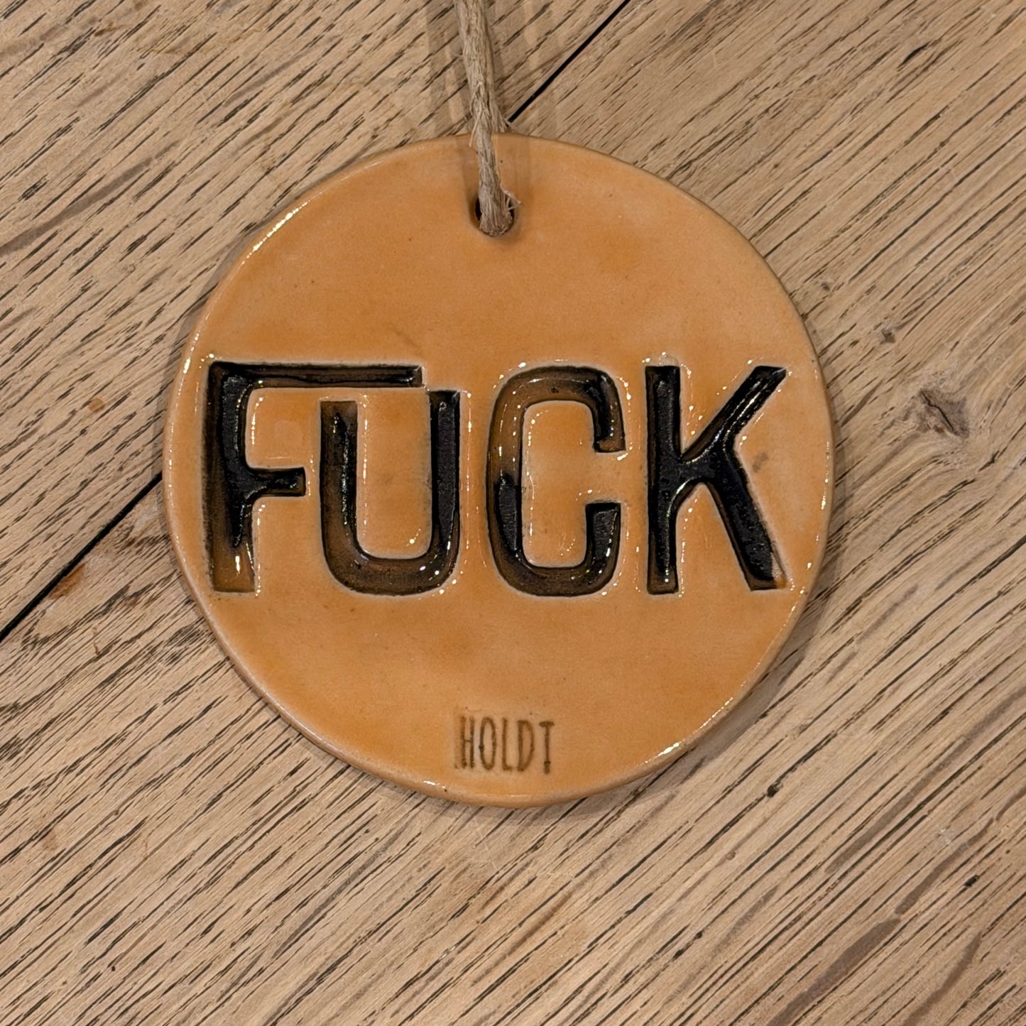 Ophæng med tekst; ‘FUCK’, lys orange