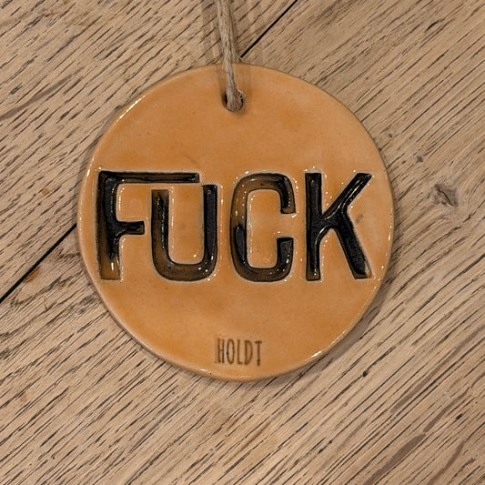 Ophæng med tekst; ‘FUCK’, lys orange